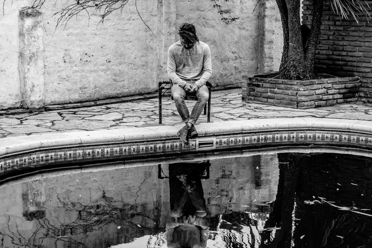 Introverted guy watching his own reflection on the water
