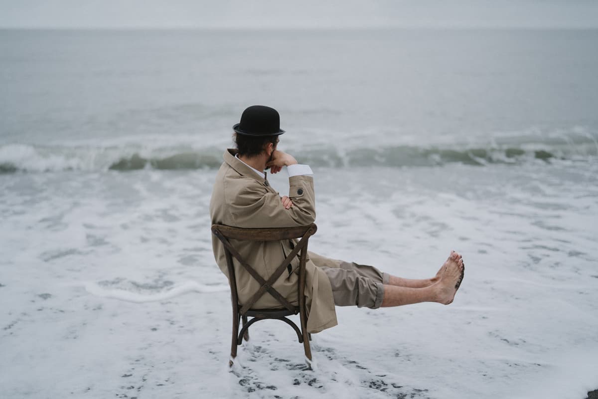 man have a habit of sitting on a wooden chair in the sea